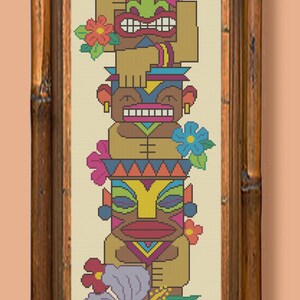 May include: A colorful tiki totem with four faces, each with a unique expression. The totem is decorated with flowers and leaves, including a hibiscus flower. The totem is framed in a brown wooden frame.