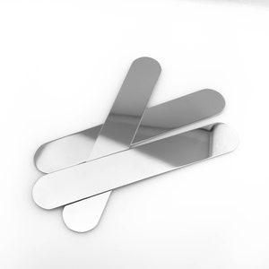 May include: Three silver metal spatulas, arranged in a criss-cross pattern, on a white background.