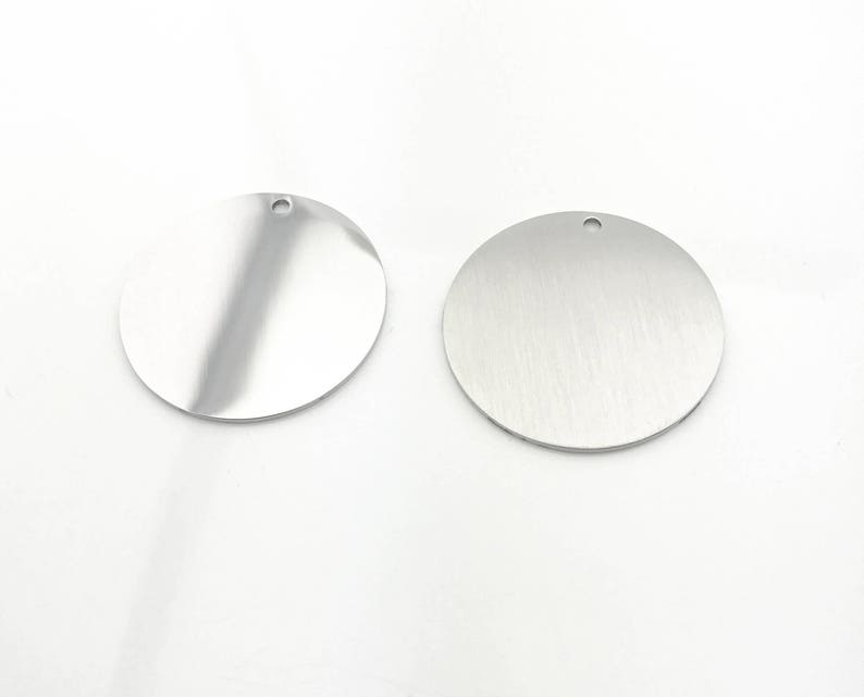 May include: Two silver round metal tags with a hole at the top. The tags are blank and ready for personalization.