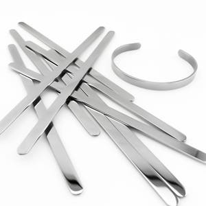 May include: A set of silver metal bracelet blanks, including a single, round, open-ended bracelet. The bracelet blanks are flat and straight, with rounded ends.