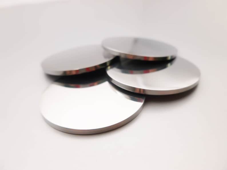 May include: Four silver-colored round coasters stacked on top of each other.