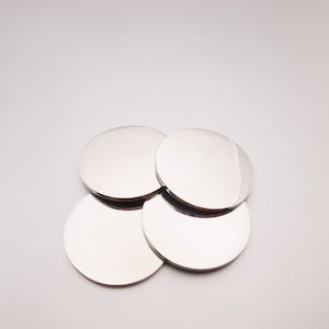 May include: Four silver round coasters stacked on top of each other.