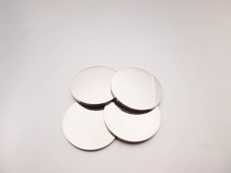 May include: Four silver round coasters stacked on top of each other.