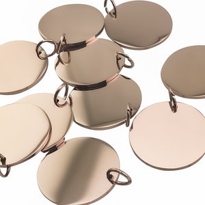 Peut inclure: Plusieurs disques métalliques de couleur or rose, certains ronds et d'autres ovales, avec de petites boucles. Les surfaces réfléchissantes des disques sont disposées sur un fond blanc. Idéal pour la fabrication de bijoux ou d'autres projets d'artisanat.