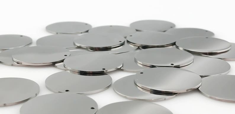 Pu&ograve; includere: Un mucchio di dischi rotondi in metallo argentato con un piccolo foro al centro. Questi dischi sono perfetti per creare gioielli, portachiavi o altri progetti fai-da-te.