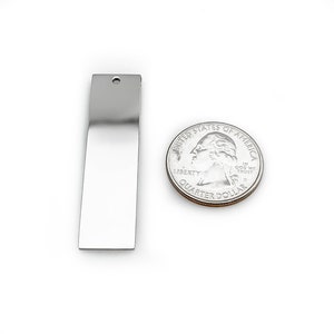 Puede incluir: Una barra de metal plateado con un agujero en la parte superior. La barra es aproximadamente del tama&ntilde;o de una moneda de 25 c&eacute;ntimos de euro.