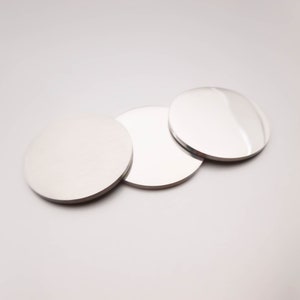 May include: Three round, silver-colored, reflective discs. The discs are arranged in a row, with the largest disc in the back and the smallest disc in the front.