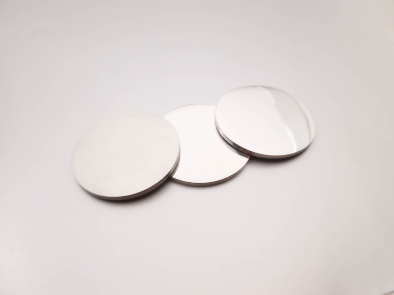 May include: Three round, silver-colored, reflective discs. The discs are arranged in a row, with the largest disc in the back and the smallest disc in the front.