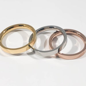 May include: Three simple wedding bands in gold, silver, and rose gold.
