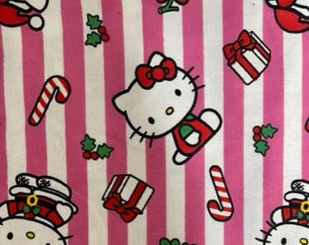 May include: Fabric with a pink and white striped design, showcasing a repeating pattern of Hello Kitty characters in Santa hats, candy canes, gift boxes, and holly sprigs. The fabric has a festive, holiday theme.