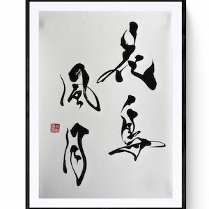May include: Black framed artwork featuring Japanese calligraphy in black ink on a white background. The calligraphy includes four distinct characters and a red stamp in the lower left corner. The artwork is displayed on a white wall.