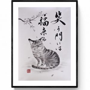 Peut inclure: Œuvre d'art encadrée en noir représentant une illustration de chat tigré souriant. Le chat est représenté en position assise, les yeux fermés. Calligraphie japonaise et branches de fleurs de cerisier sont également incluses.