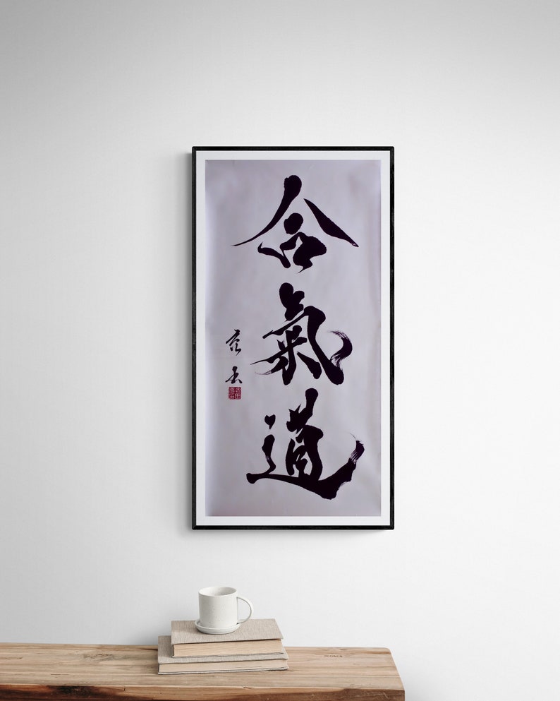 Puede incluir: Arte de caligraf&iacute;a en blanco y negro en un marco negro sobre una pared blanca. La caligraf&iacute;a dice "金 鍼 道", que se traduce como "El camino de la aguja de oro".