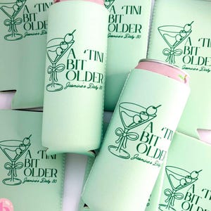 Puede incluir: Enfriadores y fundas de latas de color verde claro con un diseño de copa de martini y el texto "A Tini Bit Older Jasmine's Dirty 30". Las latas tienen tapas rosas. El diseño es en verde.