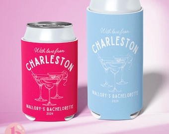 May include: Two pink and blue can coolers with white text and graphics. The text reads "With love from Charleston" and "Mallory's Bachelorette 2024". The graphics are of martini glasses.