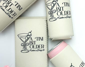 May include: A set of four white can coolers with a black design that says "A Tini Bit Older" and a martini glass with olives. The text also includes the name "Kristen's Dirty 30".