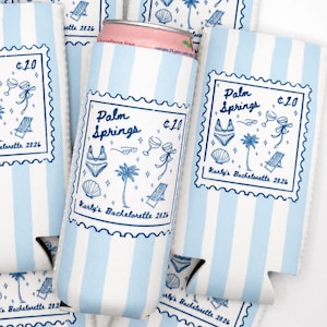 Peut inclure: Un refroidisseur de canette en mousse à rayures bleu clair et blanc avec un motif bleu en forme de timbre portant le texte Palm Springs, $20 et Karly's Bachelorette 2026. Le design inclut des illustrations de bikini, lunettes, verres, palmier et chaise.