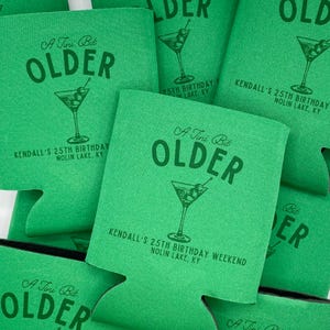 May include: Green foam can coolers with the text "A Tini Bit Older" and a martini glass graphic. The text "Kendall's 25th Birthday Weekend" and "Nolin Lake, KY" are also printed on the coolers.