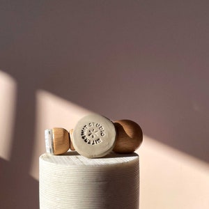 Może przedstawiać: Biała ceramiczna pieczątka z tekstem "BITTERSWEET STUDIO" i wzorem gwiazdy. Pieczątka jest przymocowana do drewnianego uchwytu.