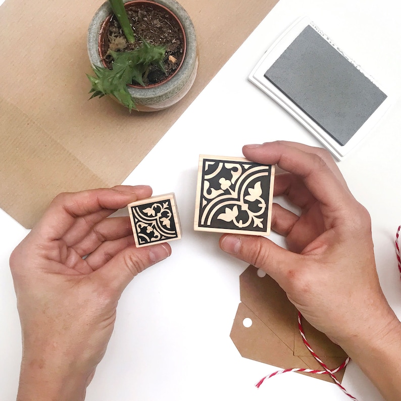 Puede incluir: Dos sellos de madera con dise&ntilde;os florales en blanco y negro. El sello m&aacute;s grande es de aproximadamente 5 cm cuadrados y el m&aacute;s peque&ntilde;o de aproximadamente 2,5 cm cuadrados.