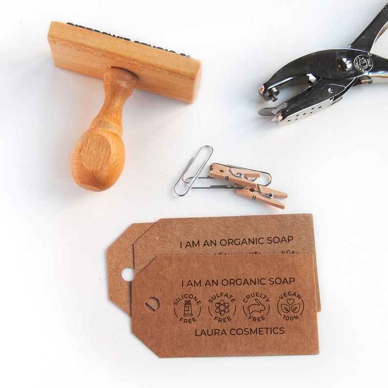 A set of kraft paper tags stamped with a soap packaging stamp. The natural brown kraft paper enhances the rustic and handmade aesthetic, perfect for branding artisan soap, solid shampoo, or natural cosmetics. The stamp design is sharp and well-defined, offering a simple, sustainable way to personalize soap labels, tags, or gift packaging.