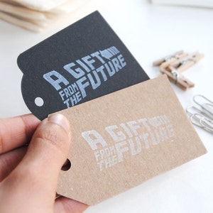 May include: Two gift tags with the text "A Gift From The Future" printed in silver on a black tag and a brown tag.