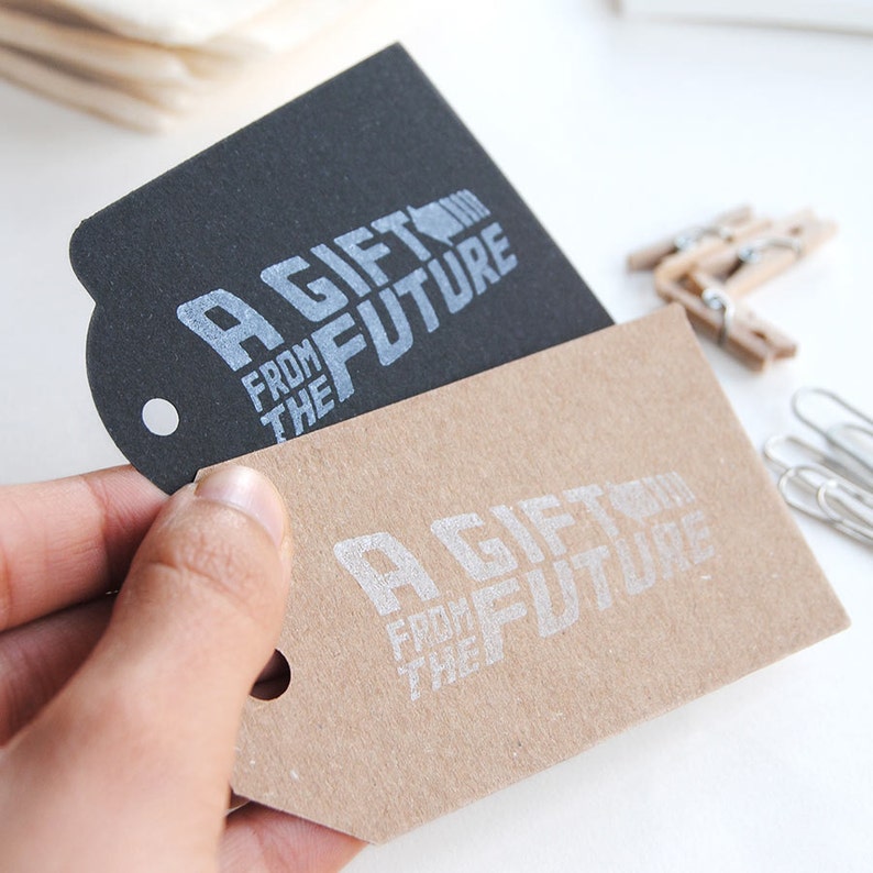 May include: Two gift tags with the text "A Gift From The Future" printed in silver on a black tag and a brown tag.