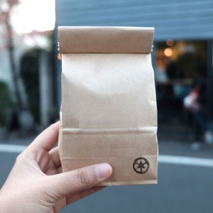 K&ouml;nnte beinhalten: Eine braune Papiert&uuml;te mit einem Recycling-Symbol in der unteren rechten Ecke.