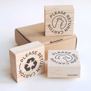 May include: Three wooden stamps with the text "Please Return Carton" and different icons: a chicken, a recycling symbol, and a duck. The stamps are on a brown cardboard box.