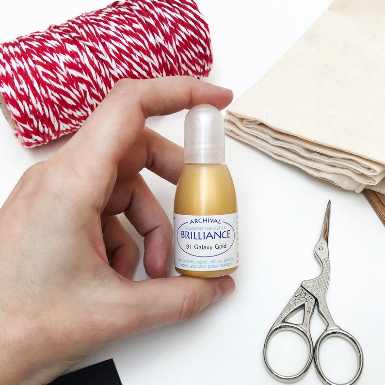 May include: A small bottle of gold archival pigment ink refill labeled "Archival Pigment Ink Refill Brilliance 91 Galaxy Gold" for ordinary paper, vellum, photos, wood, and other porous surfaces.