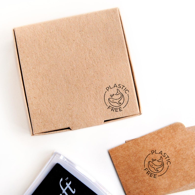 Here, the mini plastic-free whale stamp is shown printed on the side of a kraft box, showcasing how it looks when used to personalize eco-friendly packaging. The whale icon and “plastic free” message stand out clearly against the natural brown surface of the box, highlighting the sustainable and minimalistic branding that small businesses can use to promote eco-conscious shipping.