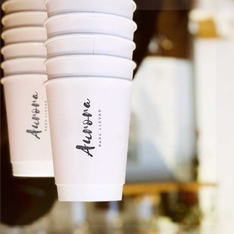 May include: A stack of white paper cups with the text "Aurora para llevar" printed on the front of the cup.