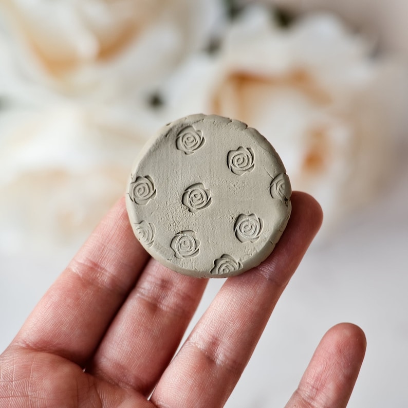 May include: A round, light brown clay disc with a repeating pattern of embossed roses.