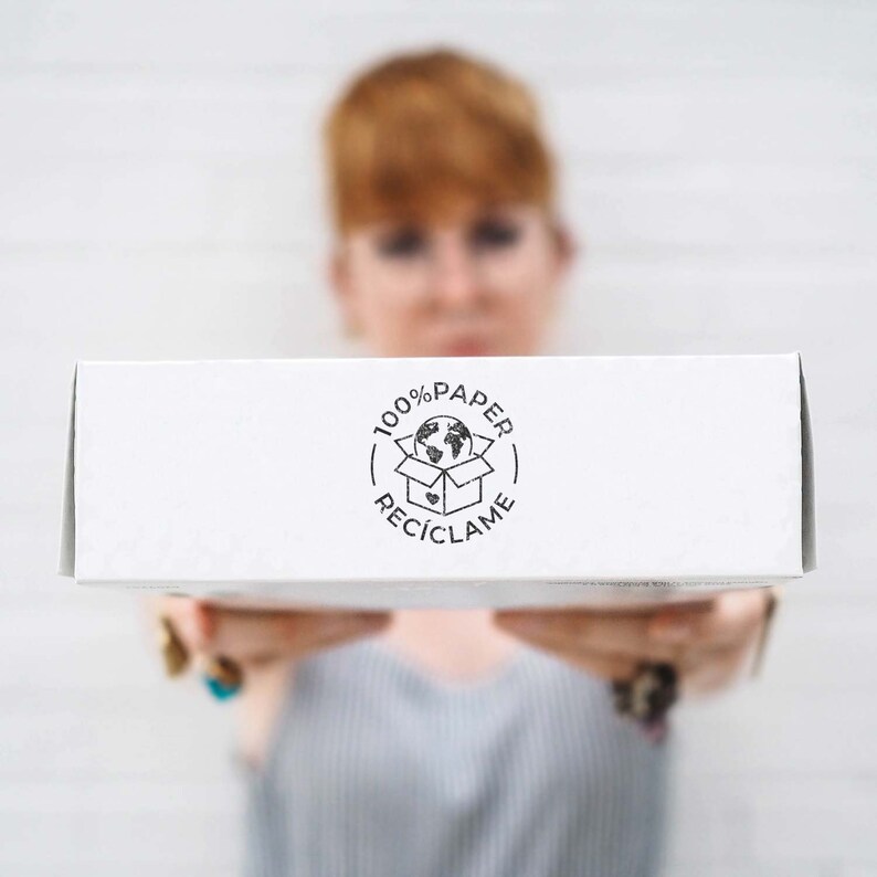 A woman holds a white box facing the camera, with the 100% Paper Recycle stamp printed on the side. This image highlights how the stamp helps businesses clearly communicate their commitment to sustainability. The simple, eco-conscious marking encourages customers to recycle packaging and support waste-free shipping practices. Ideal for online shops and eco-friendly brands.