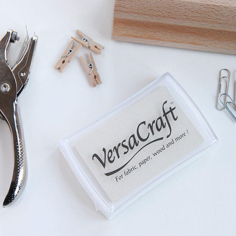 May include: A clear plastic ink pad with a white label that says "VersaCraft" and "For fabric, paper, wood and more!"