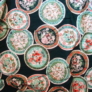 May include: A green fabric with a repeating pattern of white and red circular designs. Each circle features a stylized image of a horse-drawn carriage with a driver and passengers.
