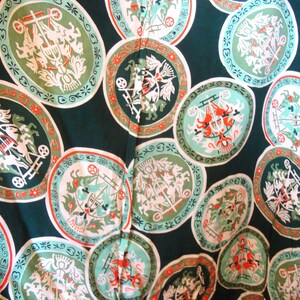 May include: A green fabric with a repeating pattern of white and red circles. Each circle contains a white design of a horse-drawn carriage with a crown on top. The background is a dark green.