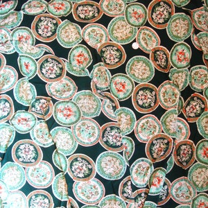 May include: Green fabric with a repeating pattern of white and red circular designs. Each circle features a stylized image of a horse-drawn carriage with a crown and other decorative elements.