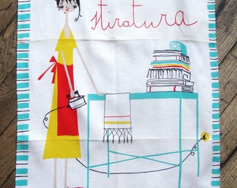May include: A white tea towel with a blue and black striped border. The towel features a cartoon illustration of a woman ironing a stack of clothes. The text "mercoledì... stiratura" is written in red and black on the towel.