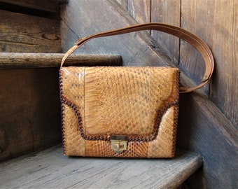 Peut inclure: Un sac à bandoulière en cuir marron avec un motif en peau de serpent. Le sac a une fermeture à rabat avec un fermoir en métal doré.