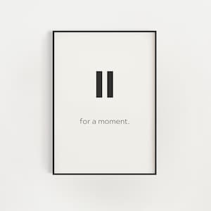 May include: A black and white minimalist print with the pause symbol and the text "for a moment."