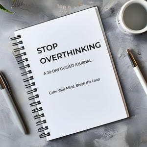 May include: A white spiral-bound journal with the words "STOP OVERTHINKING" printed on the cover. The journal is accompanied by a white pen and a cup on a gray surface. The text below reads "A 30-DAY GUIDED JOURNAL" and "Calm Your Mind. Break the Loop."