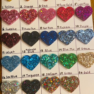 May include: A chart of 24 heart-shaped resin pieces with different glitter colors. The colors include yellow, orange, red, rose gold, light pink, sweetie, pink mix, hot pink, fuchsia, purple, velvet, midnight blue, blue, blue mix, denim, sea blue, turquoise, seafoam, green, gold, silver, black, rainbow, and Christmas.