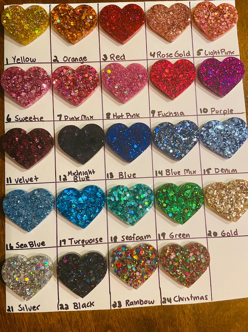 May include: A chart of 24 heart-shaped resin pieces with different glitter colors. The colors include yellow, orange, red, rose gold, light pink, sweetie, pink mix, hot pink, fuchsia, purple, velvet, midnight blue, blue, blue mix, denim, sea blue, turquoise, seafoam, green, gold, silver, black, rainbow, and Christmas.