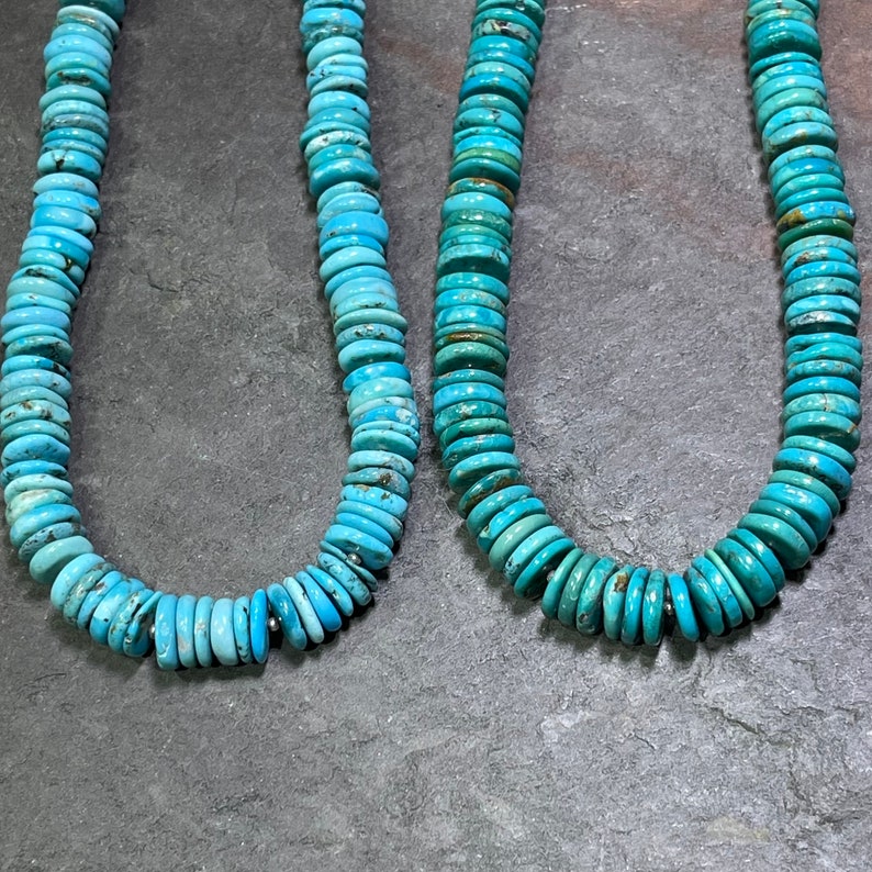 May include: Two strands of turquoise beads, each with a different length, are displayed on a grey background. The beads are a light blue colour and are round and flat.