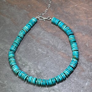 May include: A turquoise and silver necklace with round turquoise beads. The necklace is made of a silver chain and has a clasp.