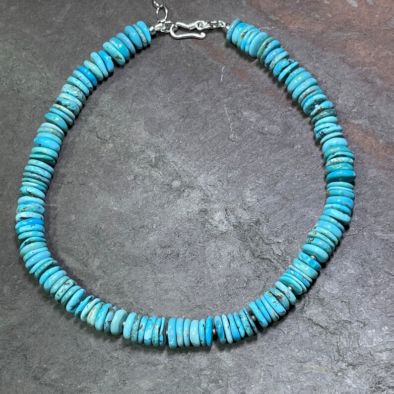 May include: A turquoise necklace with a silver clasp. The necklace is made of round, flat turquoise beads.