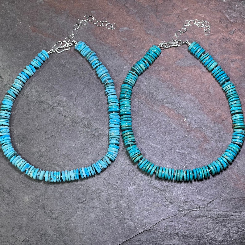 May include: Two turquoise blue beaded necklaces with silver clasps. The necklaces are made of flat, round beads and are strung on a silver chain.