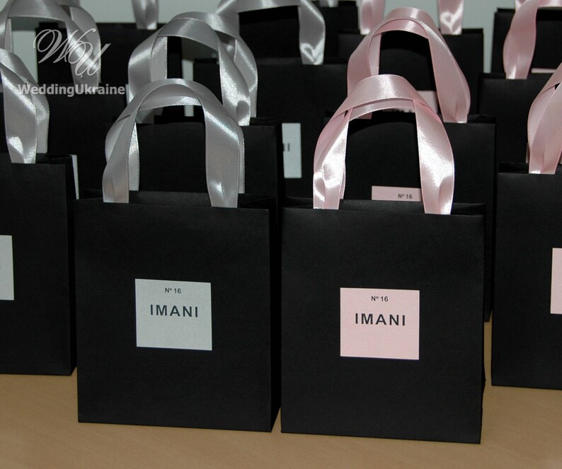 May include: Black gift bags with pink ribbon handles and a white label that says "N&deg; 16 IMANI".