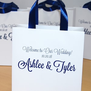 Gepersonaliseerde huwelijksgeschenkzakjes voor hotelgasten - Elegante welkomstzakjes voor bruiloften met marineblauwe satijnen linthandvatten en uw namen